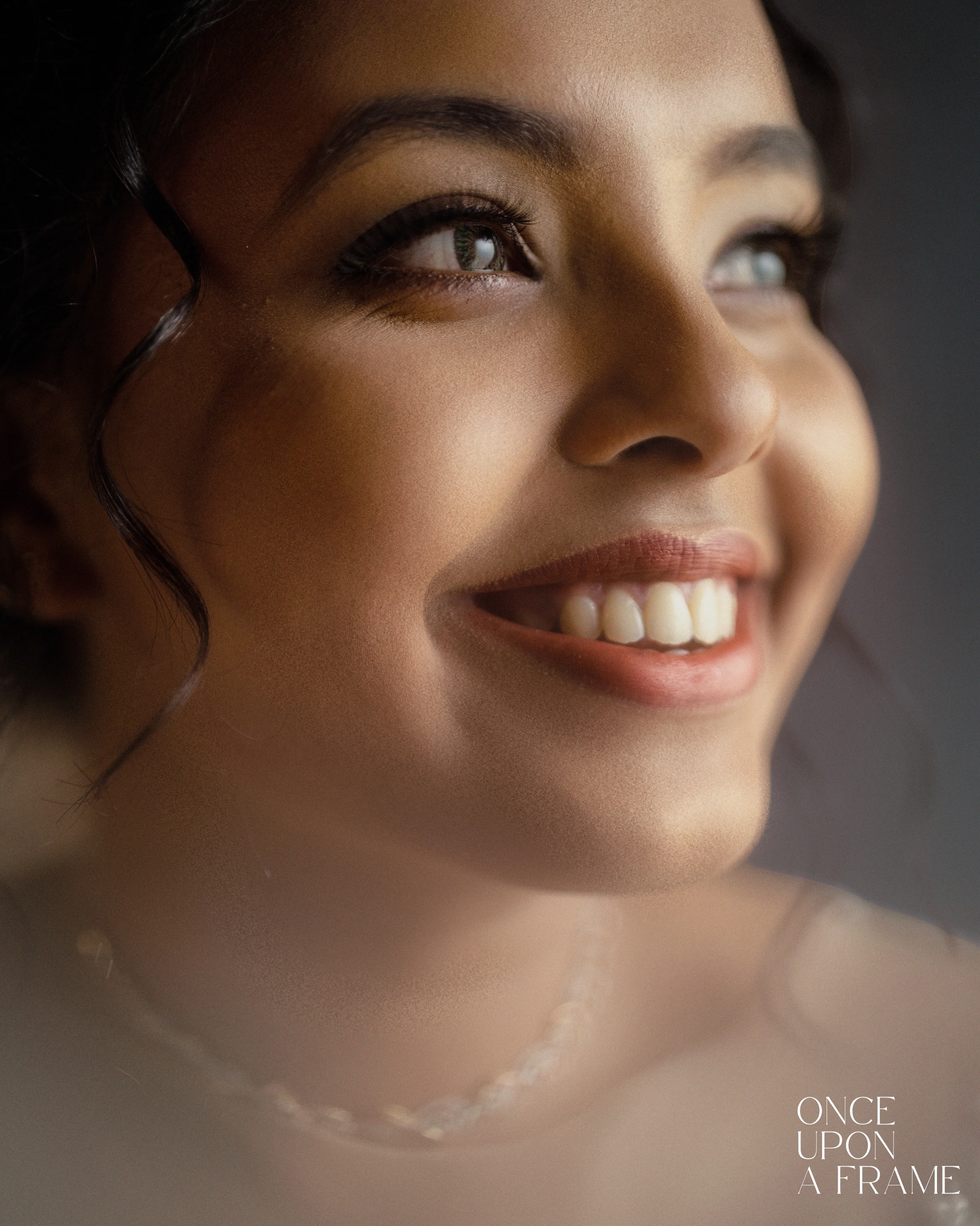 A softly lit close-up portrait of a smiling bride