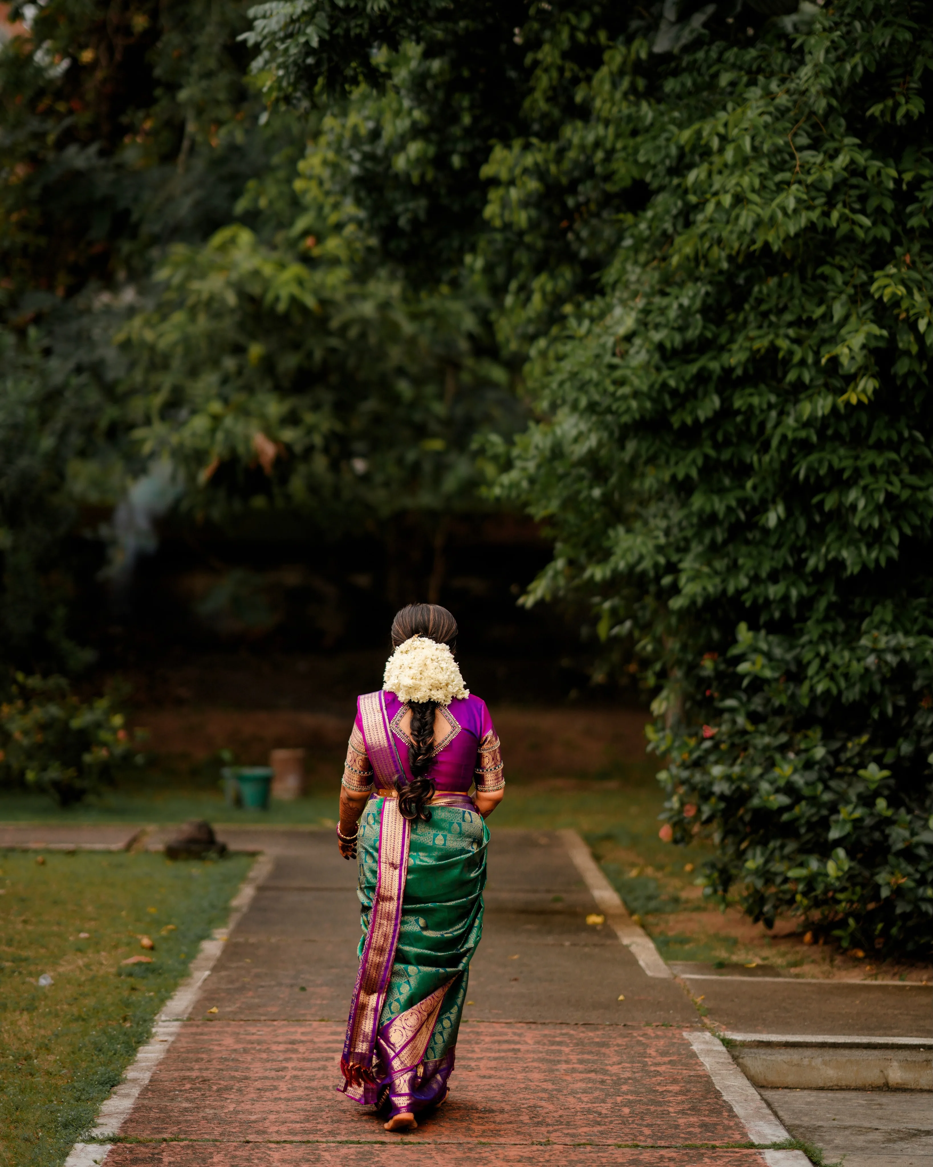 A bride walking along a garden path in traditional attire